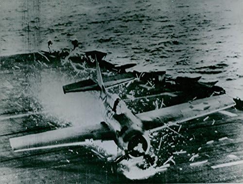 תצלום וינטג 'של מטוס קרב Wildcat 39; מדחף מפיץ את סיפון הטיסה מעץ של נושאת מטוסי צי האוקיאנוס השקט האמריקני, ומשאיר מסלול של קינדל. -